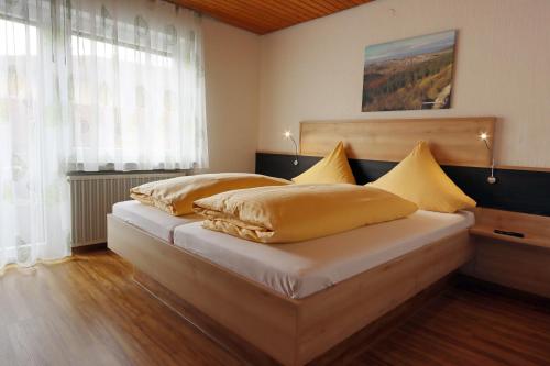 a bedroom with a bed with yellow pillows on it at Hotel Heuberger Hof, Wehingen in Wehingen