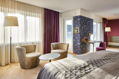 a hotel room with a bed and two chairs and a table at Sorell Hotel Seefeld in Zürich