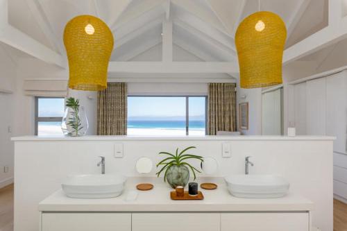 a bathroom with two sinks and a view of the ocean at Cape Beach Villa in Noordhoek