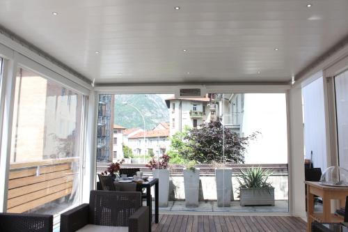 een balkon met een tafel en stoelen en een groot raam bij SoloSonno in Lecco