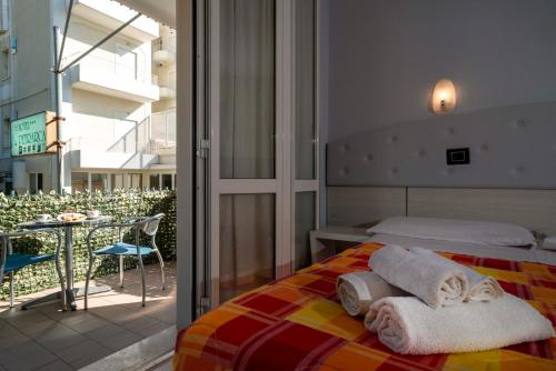 een slaapkamer met een bed en een balkon met een tafel bij Hotel Petrarca in Rimini
