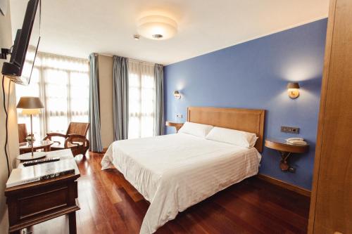 1 dormitorio con cama y pared azul en Hotel El Sella en Cangas de Onís