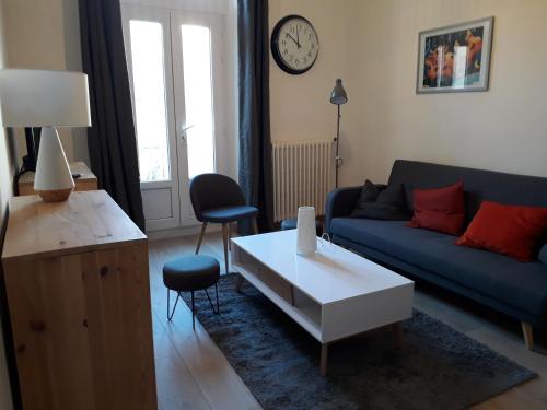 塞特港的住宿－Le V Génie verdure et calme à deux pas des Halles de Sète，客厅配有蓝色的沙发和白色的咖啡桌。