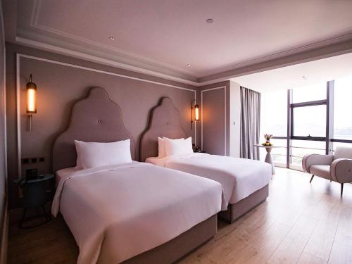 a hotel room with two beds and a large window at Mercure Xiamen Zhongshan Road Pedestrian Street Seaview in Xiamen