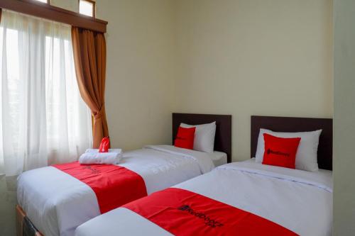 two beds in a room with red and white at RedDoorz Syariah near Alun Alun Kebumen in Kebumen