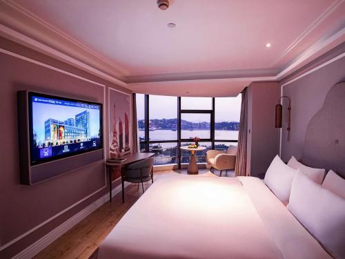a hotel room with a bed and a flat screen tv at Mercure Xiamen Zhongshan Road Pedestrian Street Seaview in Xiamen