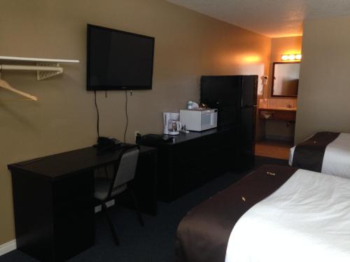 a hotel room with a desk and a bed at Chinook Country Inn in Sundre