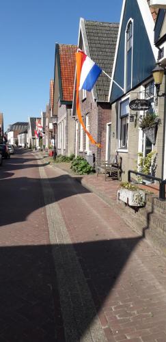 a flag flying on a street next to houses at Bed en Breakfast kamers en meer Het Spookhuis in Den Hoorn