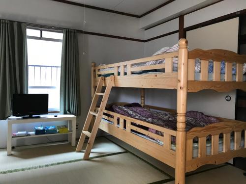 a bedroom with two bunk beds and a television at 山下ビル503 in Sutara