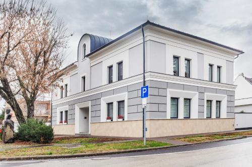 a white building with a blue parking sign in front of it at Corso Lux Apartman in Gyula