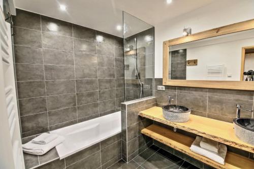 a bathroom with a tub and a sink and a mirror at Chalet L'Ecureuil in Peisey-Nancroix