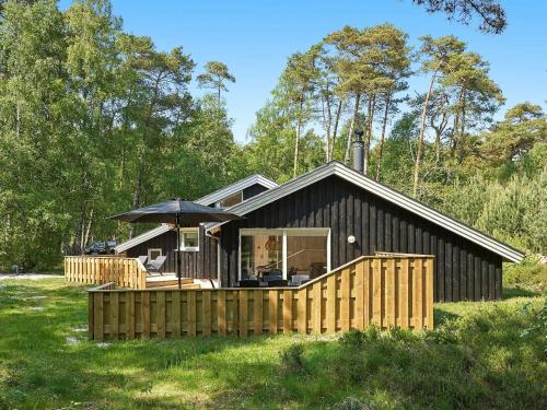 una pequeña casa con una valla de madera delante de ella en 8 person holiday home in Nex en Neksø