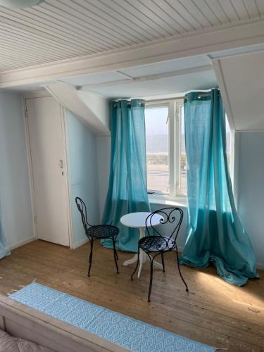 ベルゲン・アーン・ゼーにあるPacific, spectacular seaviewの椅子2脚、テーブル、窓が備わる客室です。
