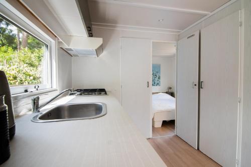 een witte keuken met een wastafel en een raam bij Luxe chalet op de Veluwe in Ermelo