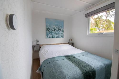 niewielka sypialnia z łóżkiem i oknem w obiekcie Luxe chalet op de Veluwe w mieście Ermelo