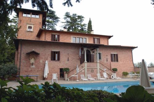 un gran edificio de ladrillo con una piscina frente a él en Villa Pambuffetti, en Montefalco