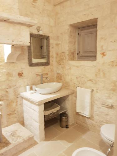 a white bathroom with a sink and a toilet at Trulli stett in Cisternino