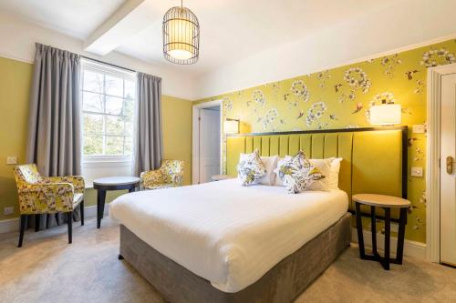 a bedroom with a large bed with yellow walls at Wisteria Hotel in Oakham