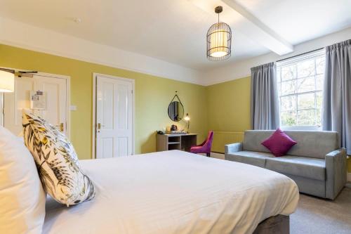 a bedroom with a large white bed and a couch at Wisteria Hotel in Oakham