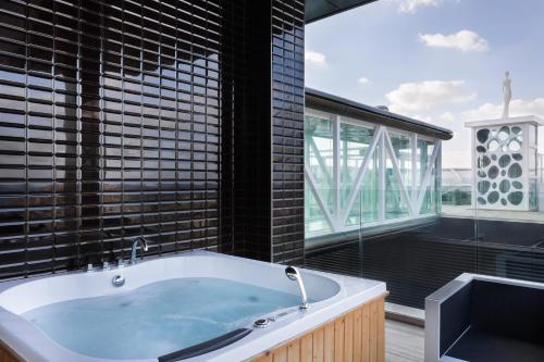 a bath tub in a bathroom with a large window at Hugo's Boutique Hotel - Adults Only in St Julian's