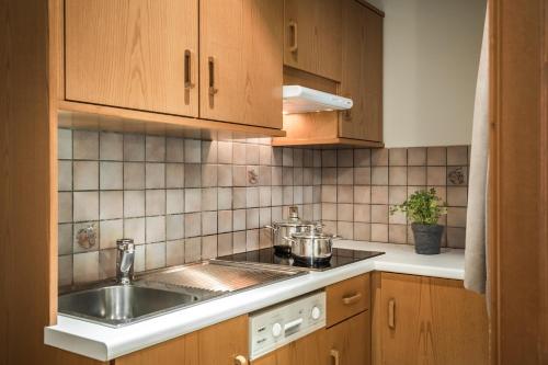 a kitchen with wooden cabinets and a sink at Residence Floralp in Colfosco