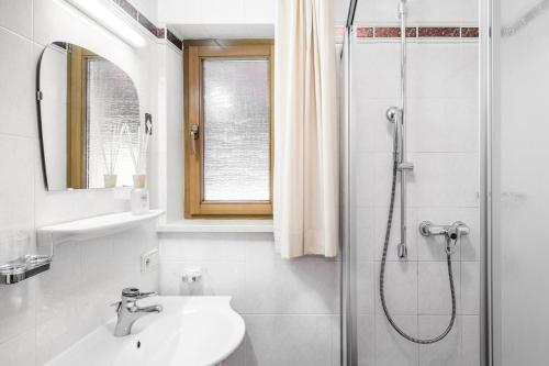 a white bathroom with a sink and a shower at Residence Floralp in Colfosco