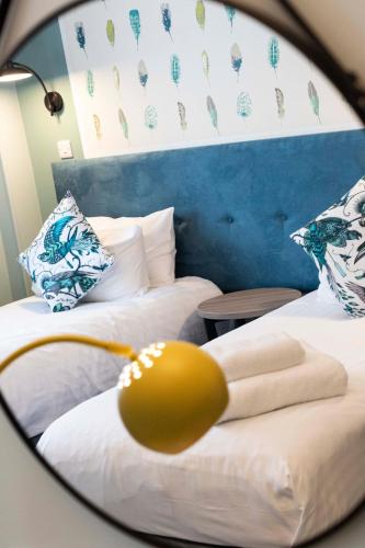 a mirror reflecting two beds in a room at Wisteria Hotel in Oakham