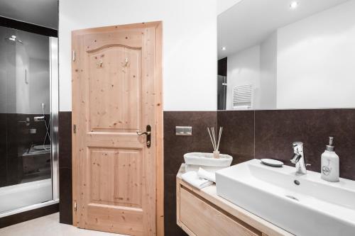 a bathroom with a sink and a wooden door at Residence Floralp in Colfosco