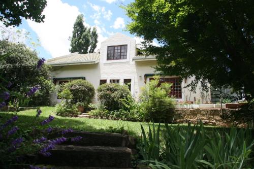 a white house with a garden in front of it at The Gate Guesthouse in Clarens