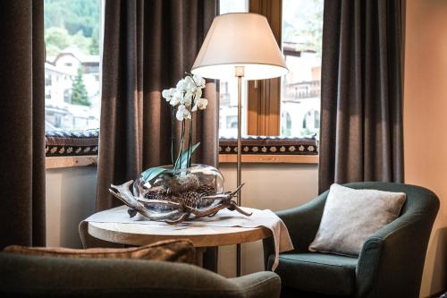 a living room with a chair and a table with a lamp at Residence Floralp in Colfosco