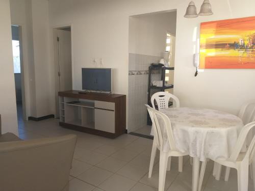 Un comedor con mesa y sillas y un televisor. en CHALÉS ENCANTOS DA ILHA, en Barra dos Coqueiros