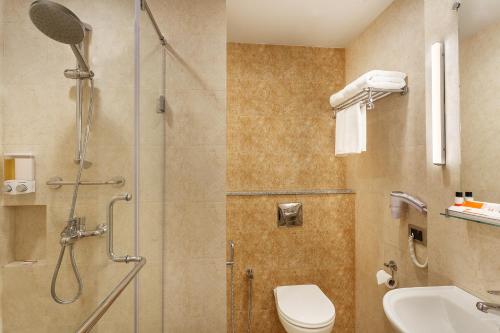 een badkamer met een douche, een toilet en een wastafel bij Ginger Surat City Centre in Surat