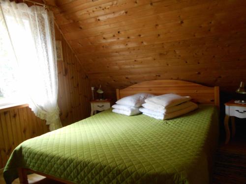 een slaapkamer met een groen bed in een houten kamer bij Ranna Talu Puhkemaja in Kassari