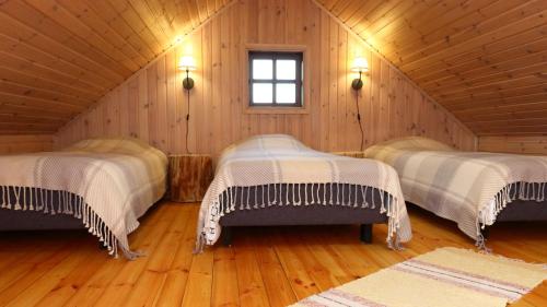 Habitación con 3 camas en una cabaña de madera en Toidupada puhkemaja, en Vidriku Asundus