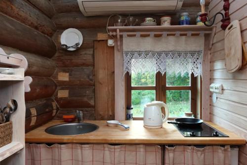 - une cuisine dans une cabane en rondins avec un évier et une fenêtre dans l'établissement Toidupada puhkemaja, à Vidriku Asundus