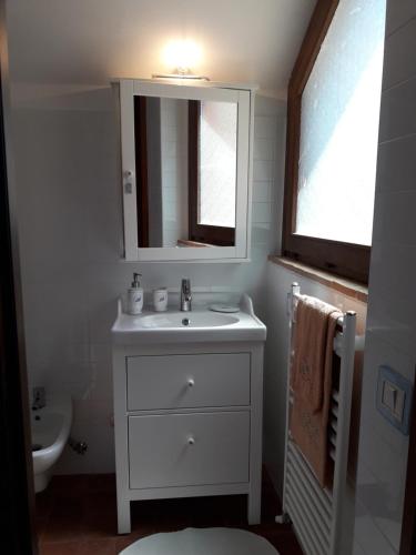 ein weißes Badezimmer mit einem Waschbecken und einem Spiegel in der Unterkunft Casa Lisa al Borgo in Ripalvella