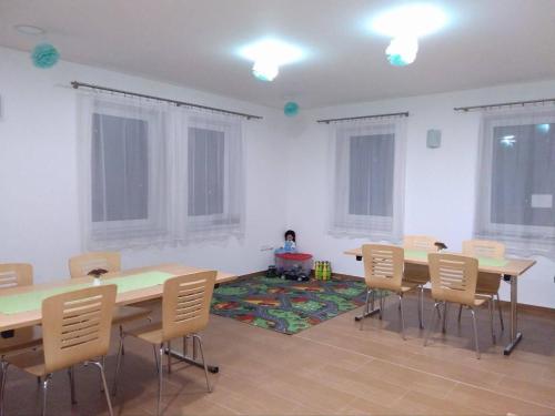 a room with tables and chairs and a girl sitting on a rug at Penzion Amalka Dobříkov in Dobříkov