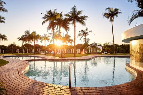 a swimming pool with palm trees in the background at Breakers Resort in Durban