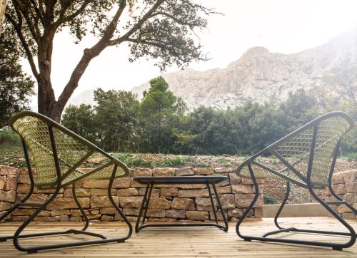 two chairs and a table on a deck with mountains at Le Relais de Saint de Ser in Puyloubier