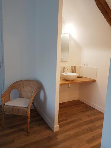 La salle de bains est pourvue d'un lavabo et d'une chaise. dans l'établissement Les gîtes du Haut Pin, à Calorguen