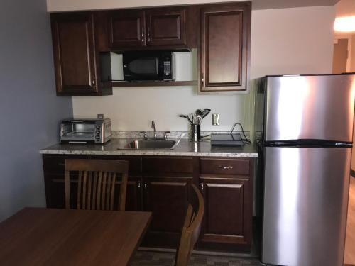 a kitchen with wooden cabinets and a stainless steel refrigerator at Travelodge by Wyndham Sydney in Sydney