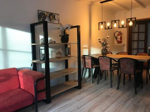 a dining room with a table and a red couch at De Specht in Bergen