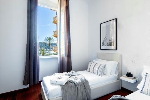 a white bedroom with a bed and a window at Butterfly Apartment in Rapallo