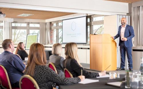 a man standing in front of a podium in a meeting room at Yarnfield Park Training And Conference Centre in Stone