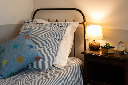 a bed with a blue and white striped pillow and a lamp at Gîtes Domaine des Machottes in Grans