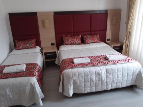 a hotel room with two beds with red and white sheets at Hotel Playa in Viareggio
