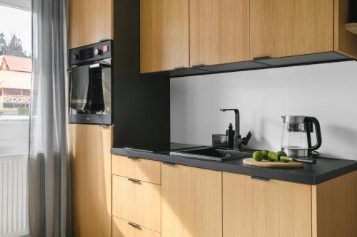 a kitchen with wooden cabinets and a counter top with a sink at Aparthotel Narciarska 2 in Korbielów