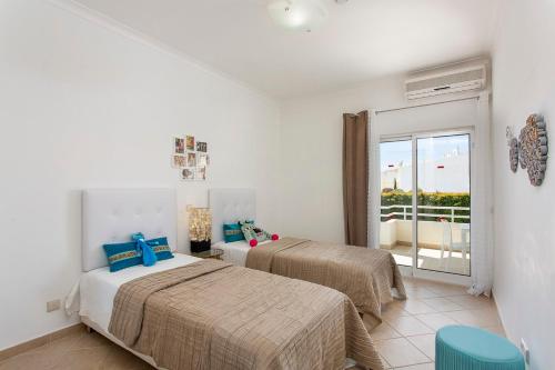 a hotel room with two beds and a balcony at Villas Mar e Brisa in Albufeira