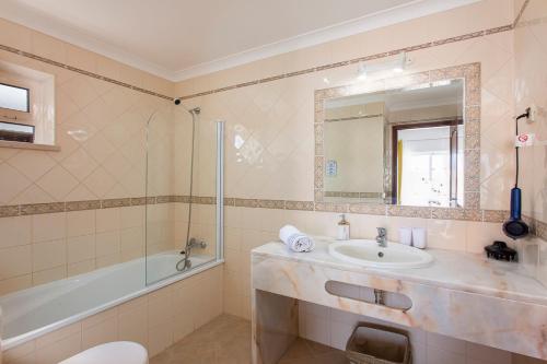 a bathroom with a sink and a tub and a mirror at Villas Mar e Brisa in Albufeira