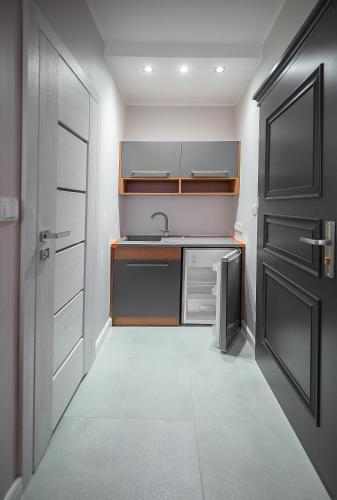 a small kitchen with a sink and a door at Kamienica Pod Neptunem in Puck